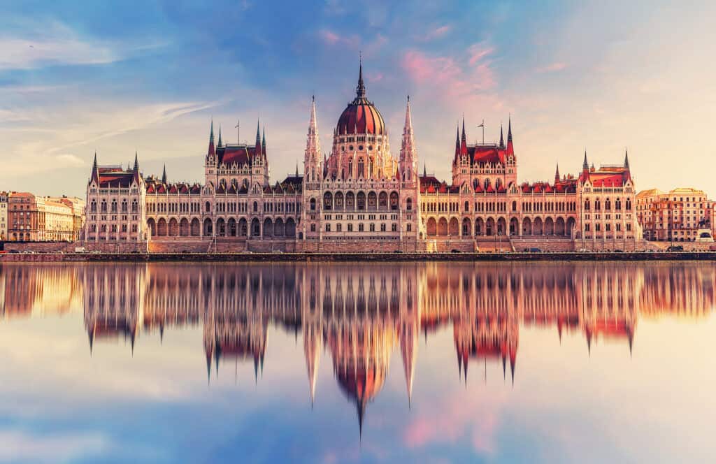Hungarian Parliament Building reflected in the Danube River at sunrise in Budapest.