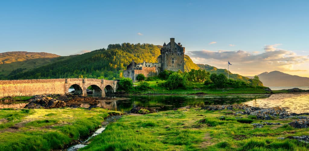 Eilean Donan Castle sits on an island in a Scottish loch, connected by a stone bridge, surrounded.