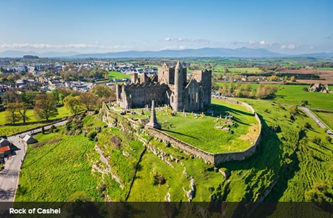 Aerial view of Caerphilly Castle surrounded by green fields and a moat in Wales.