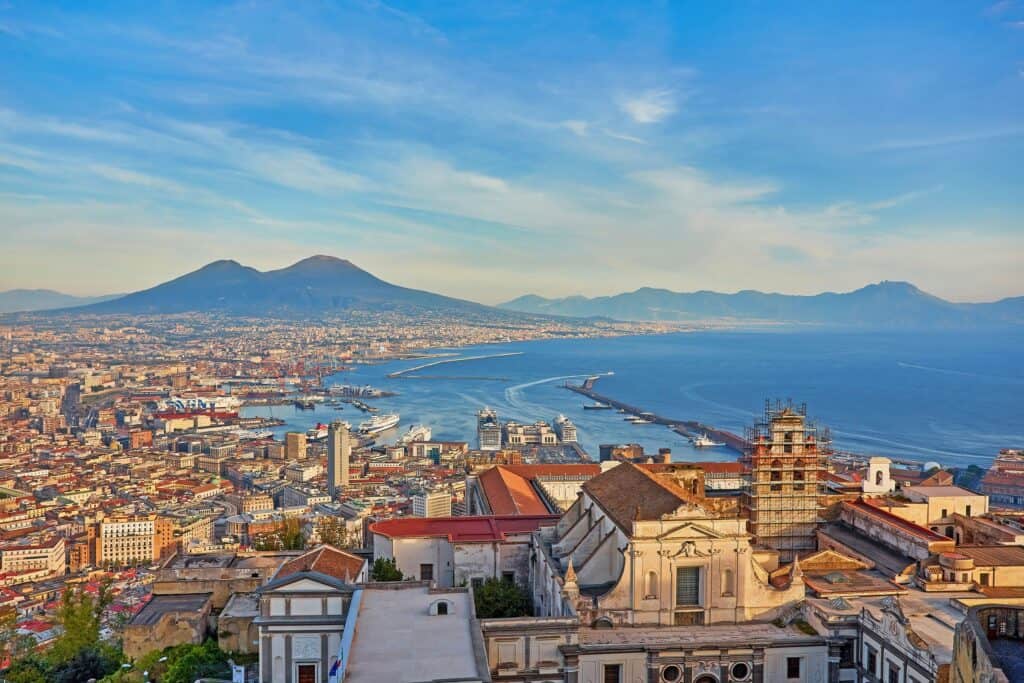 Aerial view of Naples with Mount Vesuvius, the bay, and historic buildings in the foreground.
