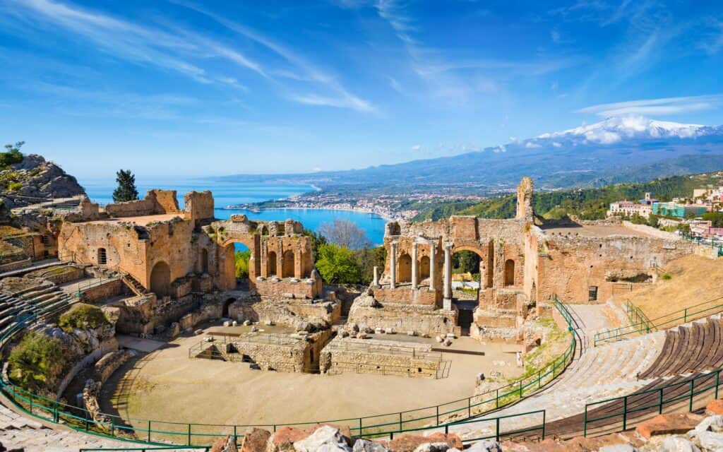Ancient Greek theater ruins overlook the Ionian Sea and coastal landscape in Sicily.